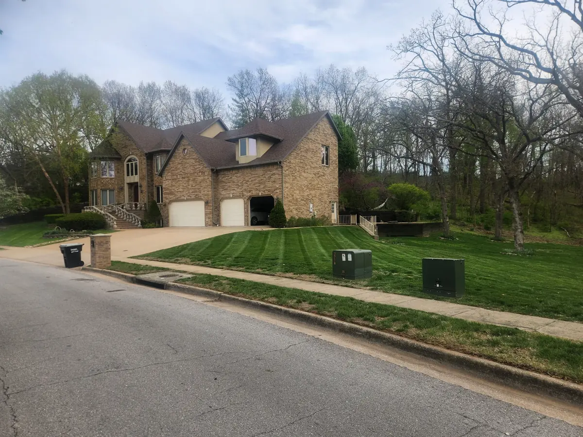 Striped front lawn extending from a driveway toward a wooded lot